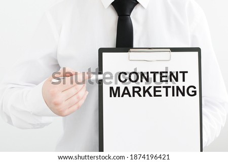 Content Marketing inscription on a notebook in the hands of a businessman on a gray background, a man points with a pen to the text