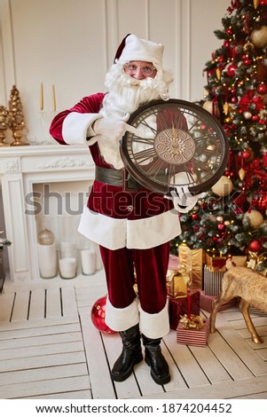 Five minutes to New year or Christmas midnight.  Happy Santa Claus shows on the clock