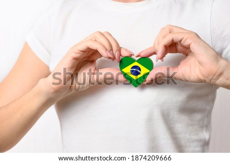 Love Brazil. The girl holds a heart in the form of the flag of Brazil on her chest. Brazilian patriotism concept