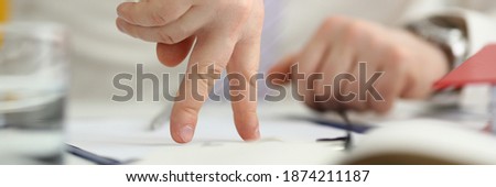 Close up of young man arm with ring doing fingers walking gesture in office Royalty-Free Stock Photo #1874211187