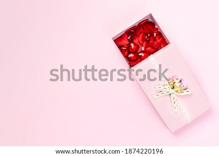 Open pink gift box full of red hearts isolated on pastel background. Valentine's Day, wedding, love concept. Top view, flat lay, copy space.