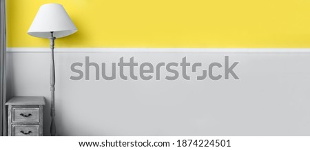 Demonstrating trendy Color of the Year 2021. Illuminating Yellow and Ultimate Gray. Duotone. Floor lamp on pastel wall background. Color Psychology. Minimalistic room interior. Depression treatment.