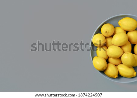Lemon fruits on plate over gray background. Top view. Copy space. Citrus fruits. Demonstrating trendy Color of the Year 2021. Illuminating Yellow and Ultimate Gray.
