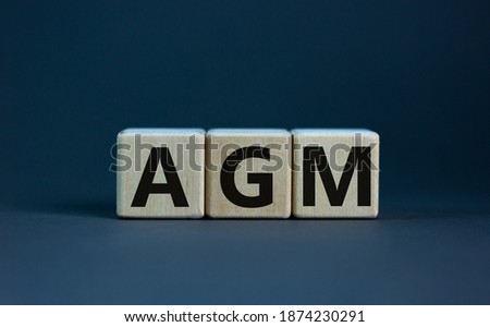 AGM symbol. Concept word 'AGM' - 'annual general meeting' on cubes on a beautiful wooden table. White background. Business and annual general meeting AGM concept, copy space. Royalty-Free Stock Photo #1874230291