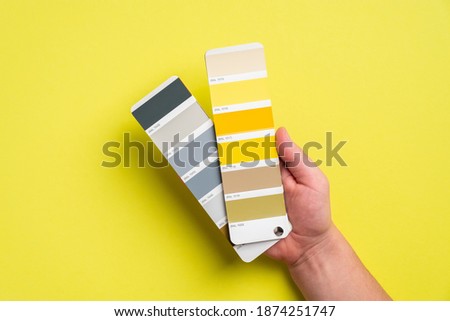 Palette with color of the year 2021 - Ultimate Gray and Illuminating yellow in man's hand. Trendy color guide palette