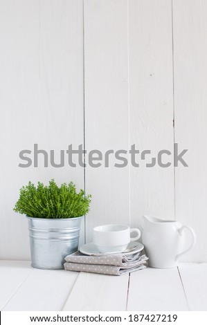 Cottage life, country kitchen decoration: a house plant in a metal pot, kitchen pottery, utensils and napkins on white painted board. Cozy home country life background is. Royalty-Free Stock Photo #187427219
