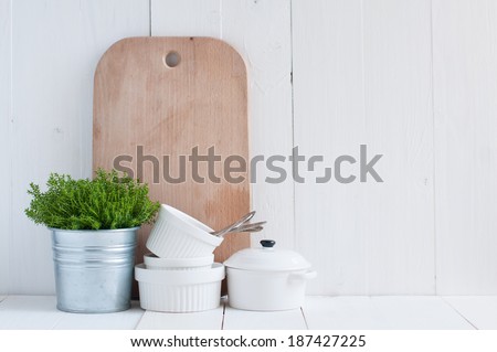Cottage life, country kitchen decoration: a house plant in a metal pot, kitchen pottery, utensils and napkins on white painted board. Cozy home country life background is. Royalty-Free Stock Photo #187427225