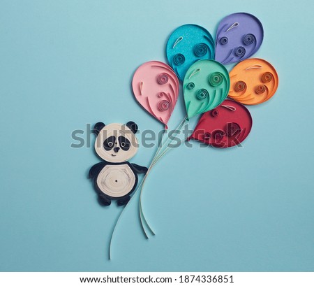 Happy cute panda with colorful balloons on blue background. Party elements. Hand made of paper quilling technique.