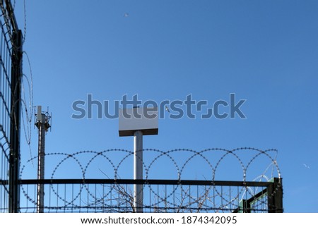 Gray metal pole behind barbed wires,electrical tower of blue sky