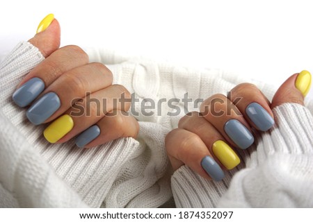 Women hands with Yellow and gray manicure. Trendy colours.