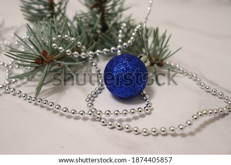 Beautiful new year card. Christmas tree and decorations - blue shiny ball, silver garland and branches of a blue spruce on a light background close-up. Festive mood. Happy holiday. Congratulation.