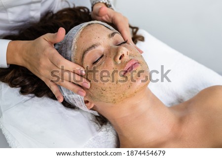 Beautiful woman receiving natural green peel facial mask with rejuvenating effects in spa beauty salon. Royalty-Free Stock Photo #1874454679