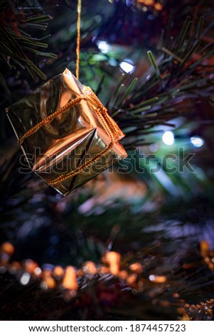 shiny gold christmas parcel decoration hanging on christmas tree