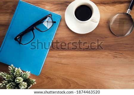 glasseson book with cup of coffee and magnifier on table