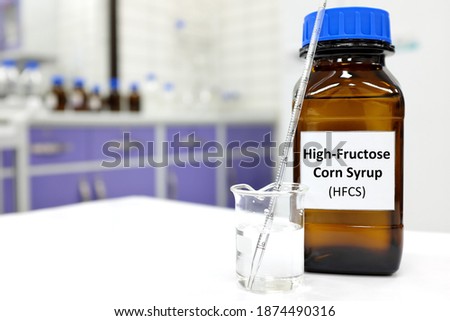Selective focus of high-fructose corn syrup or hfcs food and beverage sweetener in dark brown glass bottle inside a laboratory. Royalty-Free Stock Photo #1874490316