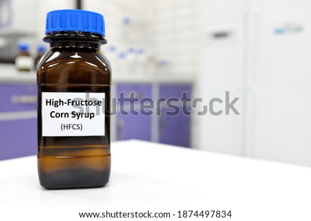 Selective focus of high-fructose corn syrup or hfcs food and beverage sweetener in dark brown glass bottle inside a laboratory. Royalty-Free Stock Photo #1874497834