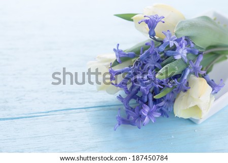 Tulips and scillas on light blue wooden background. Floral background for design. Selective focus.