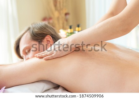 Handsome Caucasian man lying on spa bed get back massage treatment with aroma essential oil skincare from professional massage therapist at beauty salon. Wellness body massage and spa concept