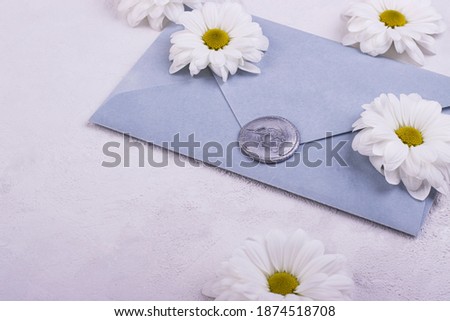 Blue handmade paper envelope with love wax seal, white flowers on the background. love note for Valentine's day, mother's day