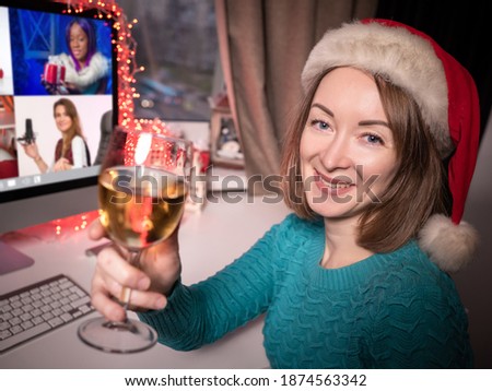 A woman in a red Santa hat celebrates Christmas at home. Online Christmas wishes during the period of the coronavirus. Remote new year's party. Happy New year greetings.