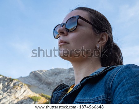 Young female tourist enjoys beautiful nature. Reflection of mountains in sunglasses, beautiful nature, valleys and mountains