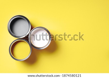 Open paint cans on yellow background. Appartment renovation, repair, building, design concept. Demonstrating trendy Color of the Year 2021. Illuminating Yellow and Ultimate Gray. Duotone.