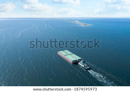 Tugboat pulling barge with cargo by water,  aerial view