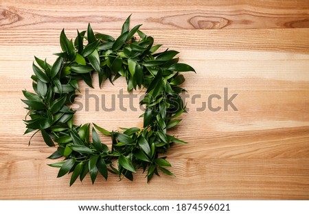 Beautiful handmade mistletoe wreath on wooden table, top view. Space for text