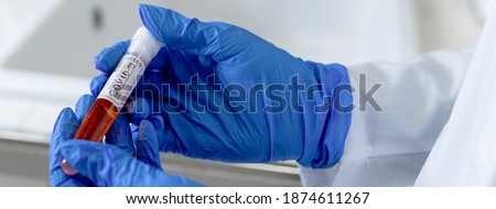 Copy space in horizontal banner close-up scientist hands with gloves holding a chemical substance in a flask with the incription covid-19. Chemical laboratory analysis and coronavirus vaccine concept.