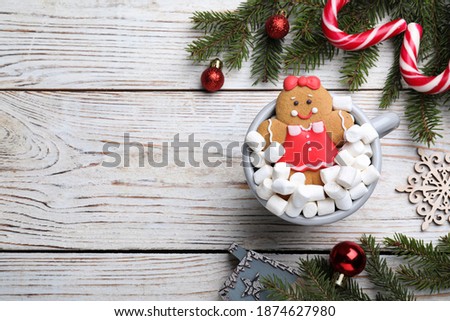 Flat lay composition with gingerbread girl on white wooden table, space for text