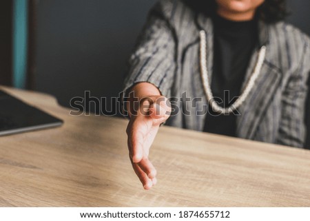Business woman sitting and gives hand for handshake proposes partnership, successful business, greeting, welcome!