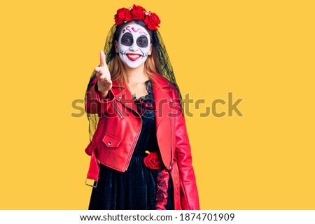 Woman wearing day of the dead costume over background smiling friendly offering handshake as greeting and welcoming. successful business. 
