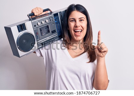 Young beautiful woman listening to music using vintage boombox over white background smiling with an idea or question pointing finger with happy face, number one