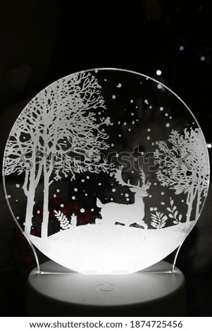 A circular mirror with fluorescent lights reflecting deer and trees. It is picture associated with Christmas 