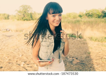 Brunette with digital  tablet outdoors colorized. Blurred motion shot/ Instagram color filter.
Mobile communications. Hipster style of life. 