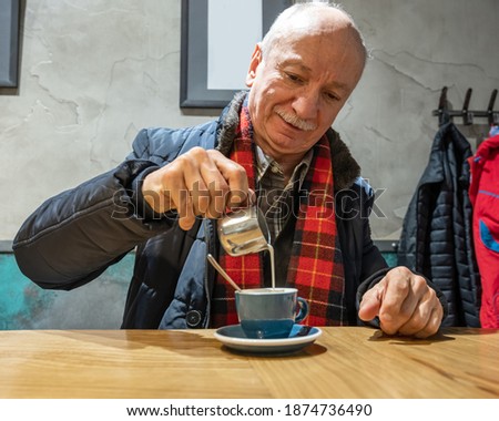 Senior man enjoying cup of coffee with coffee cream in cafe