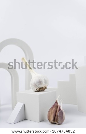 Aesthetic food photography on trendy white podium. Minimal food art still life concept.  Garlic on white background.