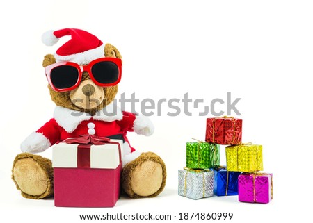 A teddy bear doll wearing santa set and glasses with many colorful gift boxes isolated on white background,Christmas day and New Year's gifts