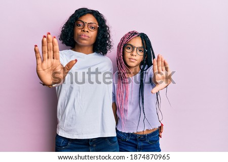 Beautiful african american mother and daughter wearing casual clothes and glasses doing frame using hands palms and fingers, camera perspective 