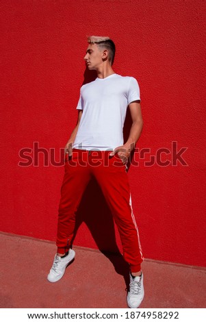 Image of handsome young smiling man standing isolated over red wall background.