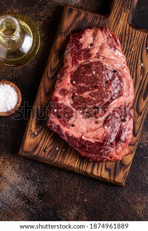 Fresh raw beef steak on a cutting wooden board, top view.