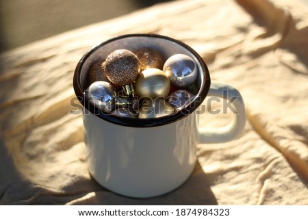 Enamel mug filled with gold ornaments. Selective focus.