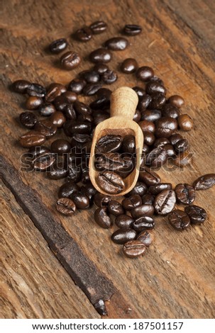 Coffee beans and wooden spoon on a wooden background. Macro picture.