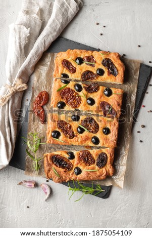 Baked focaccia with tomatoes, black olives and rosemary. Natural Italian homemade bread. Top view.