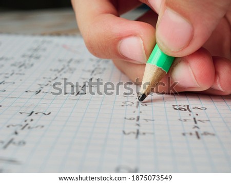 Close up look of the hand of a young girl doing maths homework, no faces shown, hand and pencil only, education concept, close up look Royalty-Free Stock Photo #1875073549