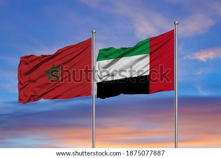 The flags of Morocco and the United Arab Emirates waving together in the blue sky Royalty-Free Stock Photo #1875077887