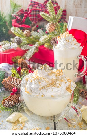 Christmas winter hot chocolates idea, recipe. Cheesecake hot chocolate with cheesecake aroma and crumbs, white chocolate and creamy milk. On white wooden table background with Christmas decor