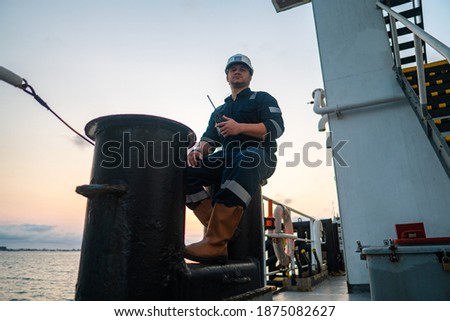 Marine Deck Officer or Chief mate on deck of offshore vessel or ship , wearing PPE personal protective equipment - helmet, coverall. Ship is on background Royalty-Free Stock Photo #1875082627