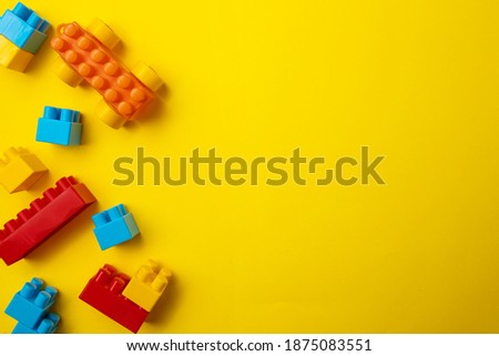 Toy blocks of different colored shapes on a yellow background.
