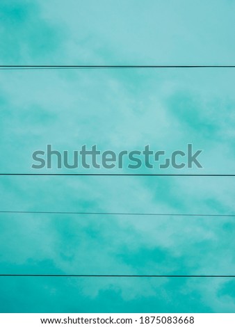 Abstract horizontal lines of electricity power cables on turquoise-colored cloudy sky background